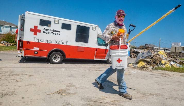 Man Carrying Red Cross Disaster Relief Supplies