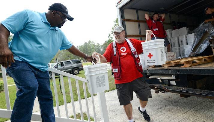 Red Cross Volunteer Handing Supplies to Man
