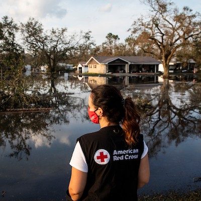 Red Cross volunteer pictured from behind, looking over flooded neighborhood after the CA atmospheric river events