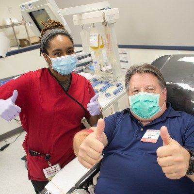 A Red Cross phlebotomist and blood donor pose for the camera