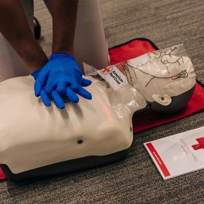 A person practices chest compressions on a CPR training dummy