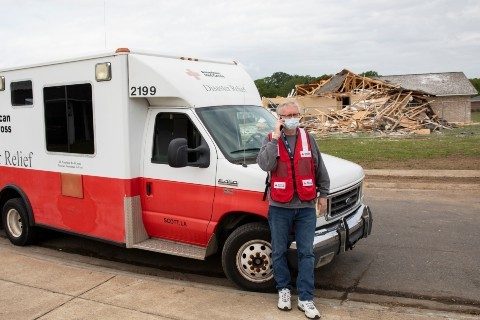 Red Cross volunteer talking on phone outside Red Cross vehicle